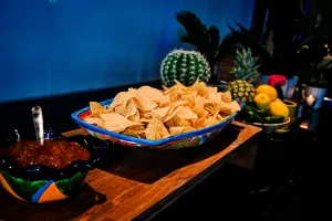 Bol grande de nachos junto a un bol mediano de salsa.