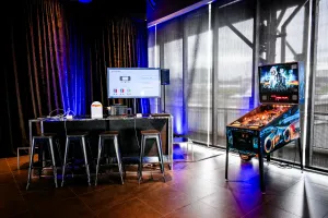 Área de videojuegos con un lounge de Nintendo Switch y sección de bar a la izquierda y una máquina de pinball a la derecha.