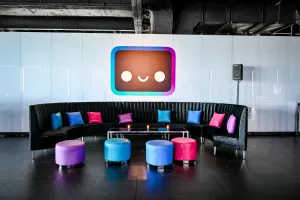 Un lounge negro con otomanas y cojines multicolores. En la pared hay un gran decal de Houston.