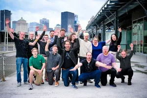 El core team de Astro posa con las manos en alto fuera del venue del meetup con el skyline de Montreal detrás de ellos.