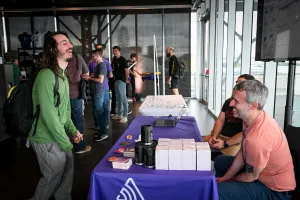 Un invitado riendo con los representantes de Sentry en su stand de sponsor.