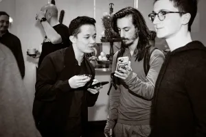 Foto en blanco y negro de un invitado leyendo la pantalla del teléfono de otro invitado.