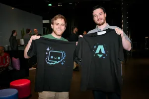 Dos maintainers de Astro sosteniendo camisetas negras. Una es de Houston y la otra del logo de Astro.