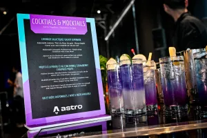 Primer plano del menú de cocktails y mocktails con cócteles morados en vasos altos a la derecha.