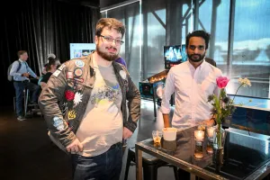 Dos invitados posan junto a una mesa alta con su comida.