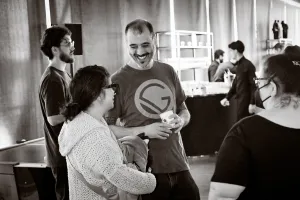 Una foto en blanco y negro de un representante de Gatsby riendo mientras escucha hablar a un invitado.