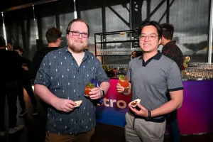 Dos invitados masculinos posando con sus aperitivos y bebidas.