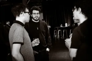 Foto en blanco y negro de un grupo de invitados hablando entre sí.
