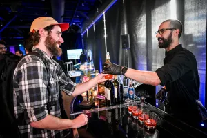 Un invitado con barba y gorra recibiendo su bebida en la barra de alcohol.