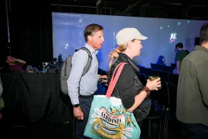 Dos invitados mayores entran al área de presentación con sus bolsas y bebidas.