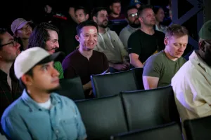 Un miembro de la audiencia sonriendo entre la multitud de personas escuchando la presentación de la keynote.