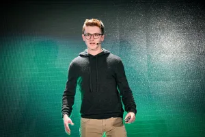 Ben Holmes en el escenario frente a una pantalla LED verde y negra.