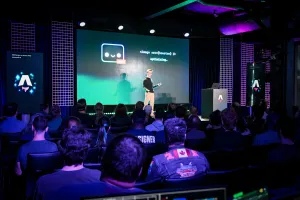 Vista desde el fondo del público. Ben Holmes está en el escenario frente a una diapositiva con Houston así como un code snippet para un componente Image.
