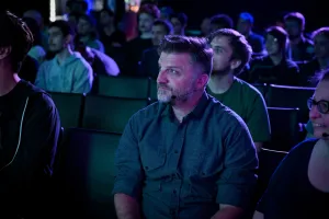Una toma de Matthew, otro orador de la keynote, en la primera fila viendo a Ben Holmes hablar en el escenario.