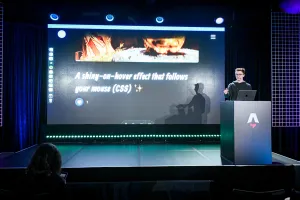 Ben Holmes en el escenario en el podio, compartiendo un demo de un efecto shiny-on-hover que sigue tu ratón.