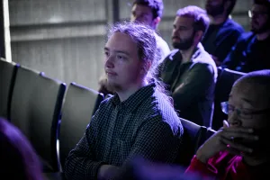 Reuben, un maintainer, viendo atentamente la presentación de la keynote desde el público.