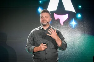 Matthew Phillips hablando en el escenario. En pantalla detrás de él está el logo de Astro Together.