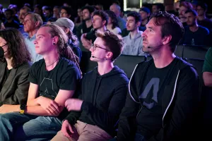 La primera fila de miembros del equipo de Astro viendo al orador de la keynote hablar en el escenario.