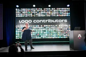 Sarah Rainsberger hablando desde el lado izquierdo del escenario, hablando sobre cómo Docs ha tenido 1.000 contributors hasta la fecha.