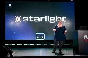 Sarah Rainsberger hablando en el escenario junto a un podio de marca Astro. El logo de Starlight se muestra junto a Houston detrás de ella.