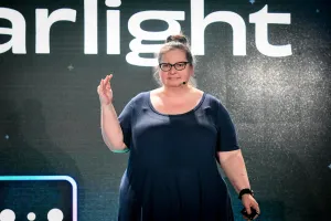 Primer plano de Sarah Rainsberger hablando en el escenario frente al logo de Starlight.