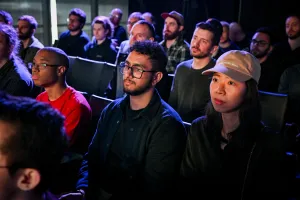 Miembros del público escuchando a Sarah Rainsberger hablar en el escenario.