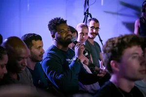 Un miembro del público sosteniendo un micrófono, preguntando a los oradores de la keynote una pregunta.
