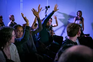 Miembros del público levantando las manos para ser elegidos para Q&A.