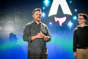 Primer plano de Matthew Phillips de pie con otros oradores de la keynote en el escenario mientras responde una pregunta del público. A la derecha, se puede ver a Ben mirando a Matthew.
