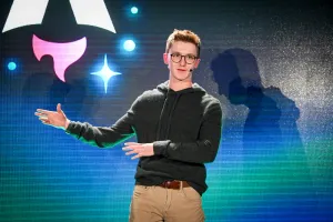 Primer plano de Ben Holmes en el escenario con las manos extendidas hacia su derecha mientras responde a una pregunta de un miembro del público.