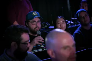Un miembro del público sosteniendo un micrófono, preguntando a los oradores de la keynote una pregunta.