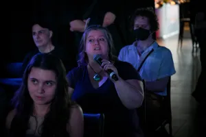 Un miembro del público sosteniendo un micrófono, preguntando a los oradores de la keynote una pregunta.