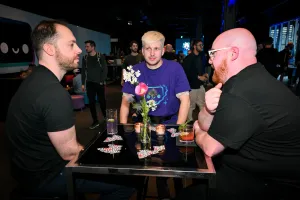 Miembros del equipo de Astro charlando con sus bebidas en una mesa alta.