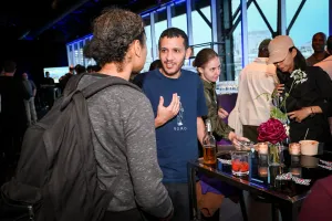 Invitados mezclándose y charlando en mesas altas con sus bebidas.