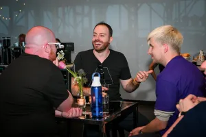 Miembros del equipo de Astro Nate Moore, Ema Stoppa, y Alex charlan entre sí en una mesa alta.