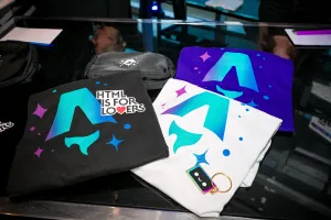 Primer plano de camisetas impresas de Astro y un sticker que dice, "HTML IS FOR LOVERS".