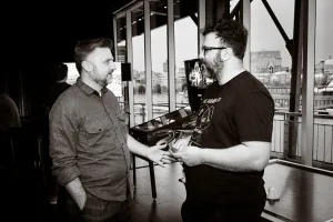 Foto en blanco y negro de Matthew Phillips charlando con un invitado.