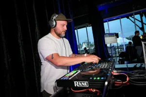 Un DJ lleva una gorra y auriculares mientras mezcla en su cabina.