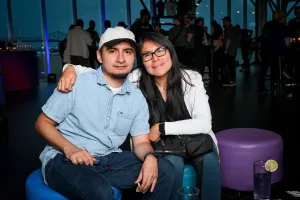 Dos invitados posan sentados en otomanas. La mujer tiene su brazo alrededor del hombre.
