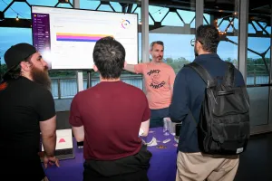 Invitados observan atentamente mientras Sentry comparte un demo en la TV en su stand de sponsor.