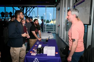 Invitados escuchan atentamente mientras Sentry explica su producto en su stand de sponsor.