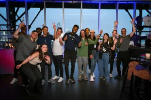 Un grupo grande de invitados posa para una foto de grupo frente a ventanas de suelo a techo.