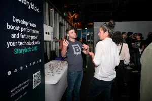 Storyblok explicando su producto a un invitado en su stand de sponsor.