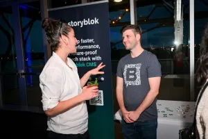 Storyblok explicando su producto a un invitado en su stand de sponsor.