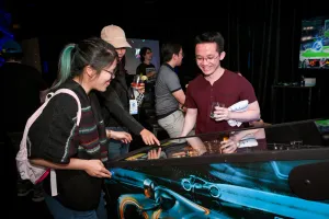 Invitados sonriendo mientras juegan al pinball.