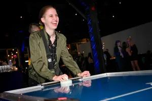 Un invitado sonríe brillantemente mientras juega al air hockey.