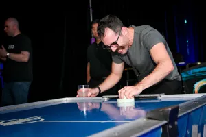 Un invitado sonríe brillantemente mientras juega al air hockey.