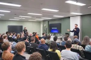 Fred presentando a los oradores frente a filas de personas en el público.