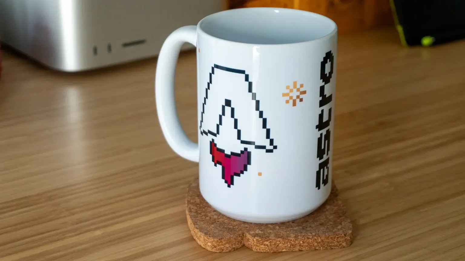Una taza blanca sobre un escritorio con un logo de Astro en pixel art.